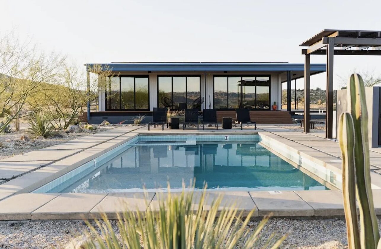 Casa Del Rio pool and glass-walled main house in the desert at golden hour